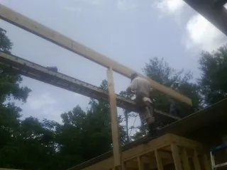 Carpenter setting a ridge beam over a new addition frame — Ice Dam Removal by Roofing Brothers in Colwell