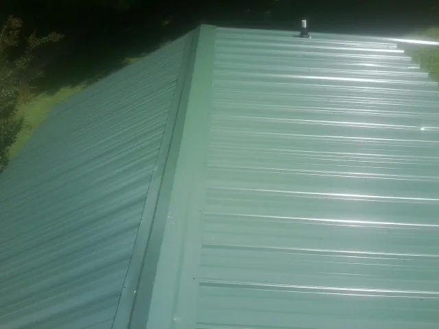 New green metal panels meeting at the ridge of a roof — Flat Roof Repair work by our crew in Colwell
