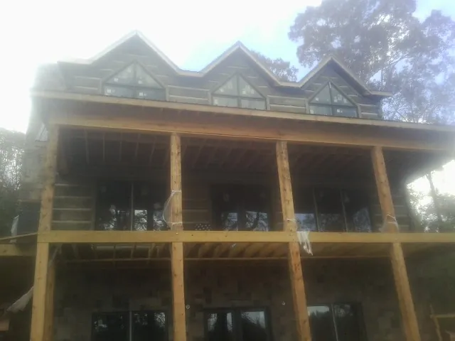 Dormers and porch framing on a large log home under construction — Roof Coating work by our crew in Colwell
