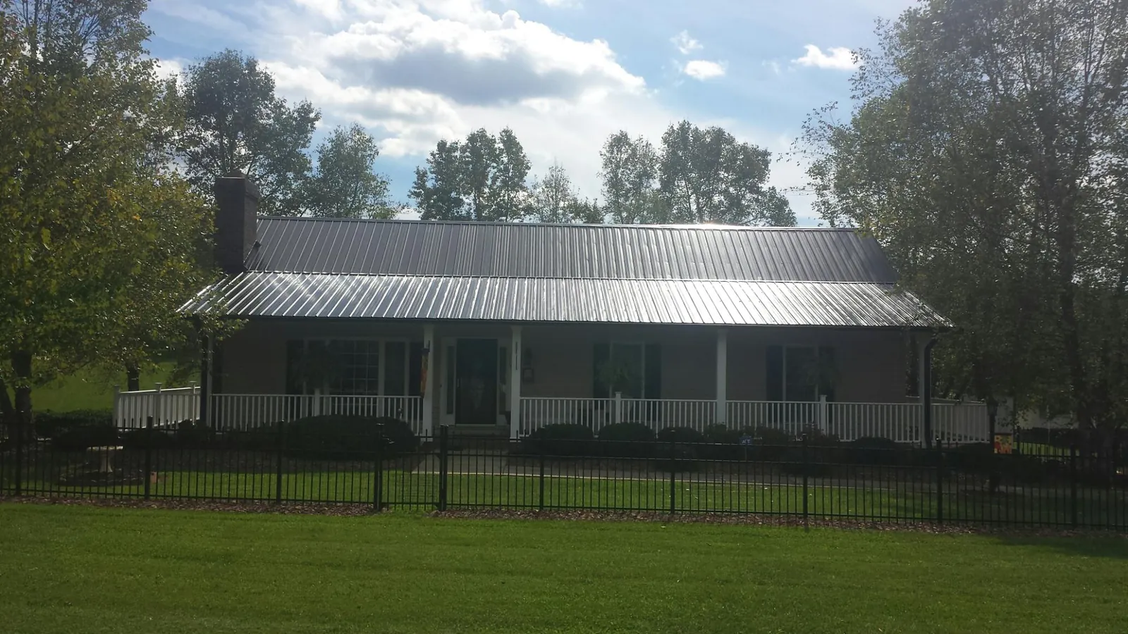 Gray metal roof on a brick ranch with a full width front porch — Gutter Guard Installation work by our crew in Colwell