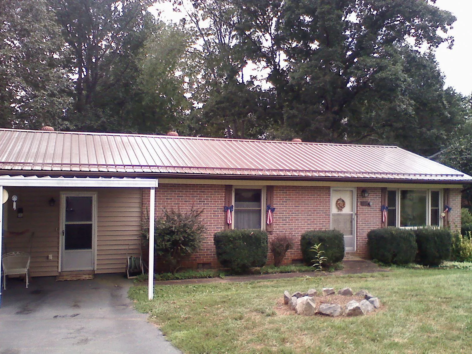 Bronze metal roof and carport on a brick ranch home — Roof Repair work by our crew in Colwell