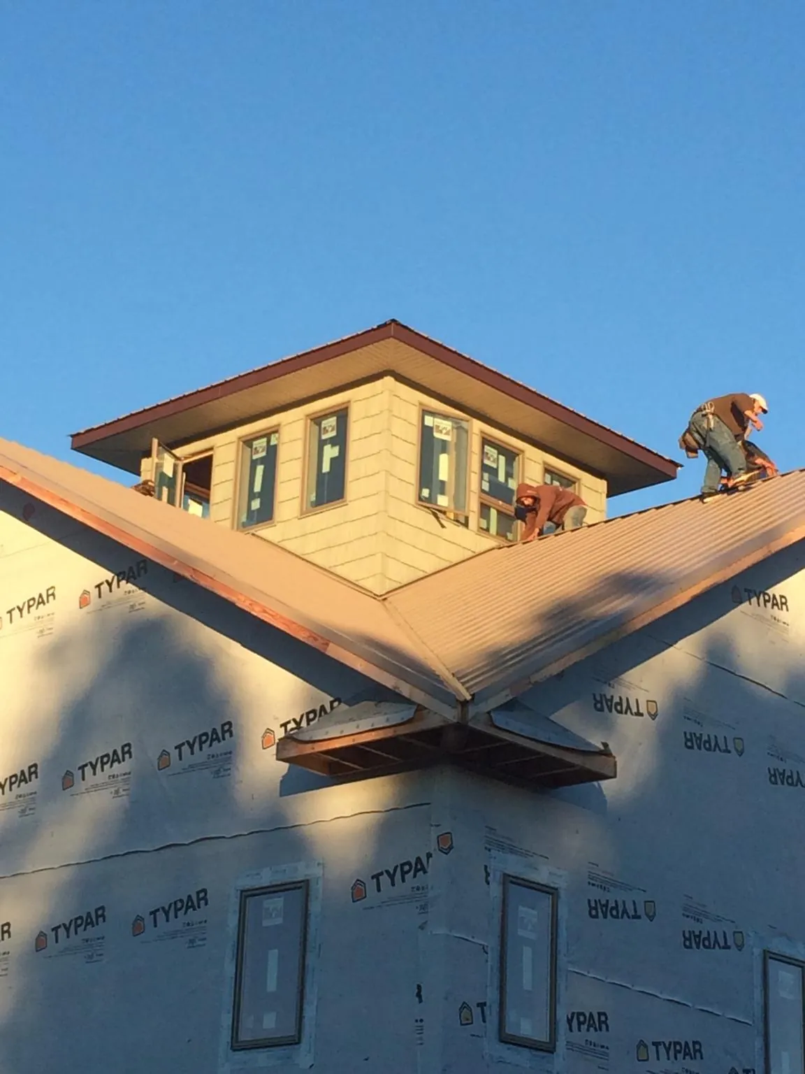 Roofers working around a rooftop cupola on a new metal roof at sunset — Roof Waterproofing in Colwell by Roofing Brothers